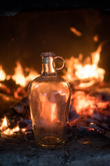 nicely shaped glass bottle in front of a fireplace with fire