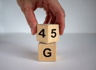 Man hand flips cube with numbers 4 and 5. 4 or 5 G technology concept. Beautiful white background, copy space.