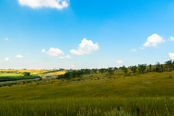 Fototapeta premium Beautiful view from the hill on the blue sky, the river and agricultural fields extending beyond the horizon.