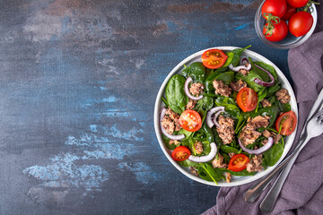 Fish salad with tomatoes, red onion and spinach. Tuna salad on a plate. Top view, copy space