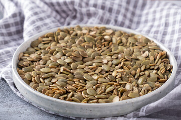 Raw pumpkin seeds on a plate. Closeup