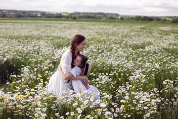 mother with daughter in a white dress and hat stand