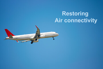 Plane flying in the sky, close-up. White passenger plane flying up, copy space. Plane in the sky with the inscription Restoring air connectivity.