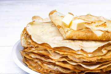 Homemade crepes with butter on white wooden background. breakfast concept.