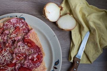 bread with salami and cheese, with onions on a wooden table