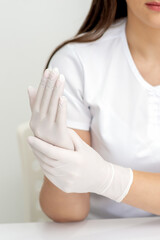 Fototapeta premium Female hands putting on protective white latex medical gloves during epidemic in quarantine