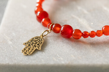 Red bracelet made out of carnelian stone with a hamsa charm