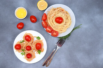 Italian pasta spaghetti with cherry tomatoes, olive oil and spices on a dark table, top view, place for text