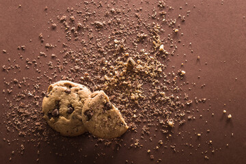 Broken chocolate chip cookie on brown background