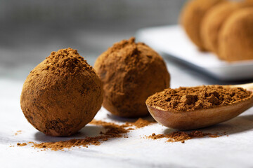 Homemade energy balls with dried apricots, raisins, dates, prunes, walnuts and cacao. Healthy sweet food. Energy balls in a plate with a wooden spoon on a marble grey background. Close up. Side view.