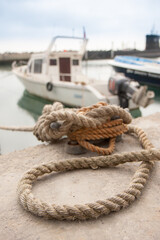 Fototapeta premium rope knotted to secure boat to dock at a harbor marina
