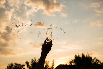 Splash of water in a glass. Flying water. A glass of water in a man's hand in the sunset.
