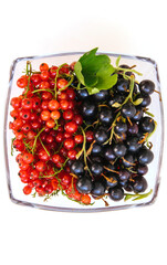 Red and black currants in a glass plate.Bright summer berries. The summer harvest.