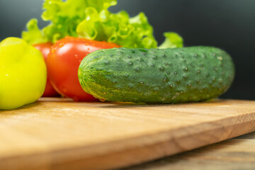 Beautiful, juicy vegetables with water drops Peppers, tomatoes, lettuce leaves, cucumber on a wooden Board close-up