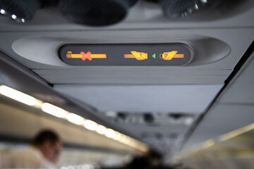 prohibition signs in airplane light up on control panel overhead with signal that shows crossed...