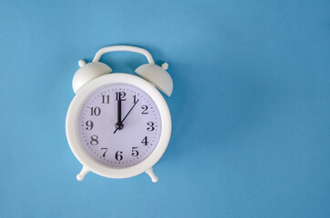 White alarm clock on blue background, copy space