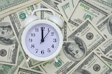 white alarm clock stands on dollar bills. Concept of business planning and Finance.