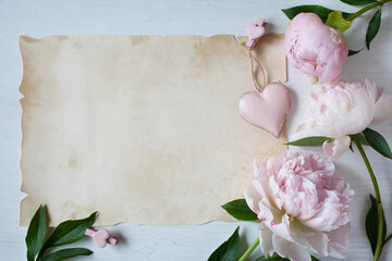 Background with pink peonies, decor heart and paper for congratulations text. © tachinskamarina