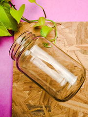 Glass jar on wood and pink background and plant 