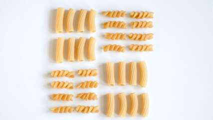 Different kinds of raw pasta on white background, vegetarian food knolling concept. 