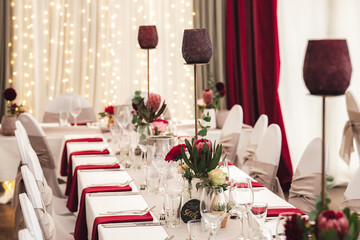 Colorful flowers on table with white table cloth. Festive table setting with cutlery, napkins and glasses. Celebration, birthday or wedding concept.