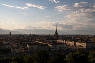 Foto di panorama urbano della città di Torino con vista montagne all'orizzonte e nuvole nel cielo.