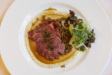 Thin slices of ribeye with lentils and creamy mustard