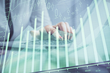 Double exposure of businesswoman hands typing on computer and financial graph hologram drawing. Stock market analysis concept.