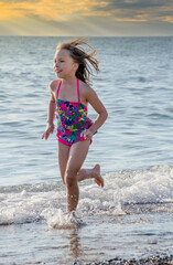Active Little girl running on a sandy  beach