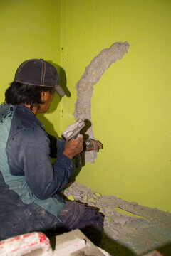 TRABAJADOR MARTILLANDO UNA PARED EN REPARACI&Oacute;N