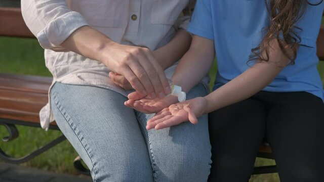 Use a disinfectant on hands. A woman treats the child's hands with a sanitizer.
