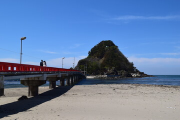 白山島（東北の江ノ島）／ 山形県鶴岡市の由良海岸沖にある白山島（はくさんじま）は、「日本の渚百選」と、「快水浴場百選」に選ばれた由良海岸のシンボル的な島で、その景観から「東北の江ノ島」と呼ばれています。由良海岸から島までは赤い白山橋が架けられており、歩いて島に渡ることが出来ます。