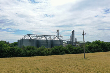 Fototapeta premium Agricultural silos on a farm, photos from above with a drone. Industrial agricultural granary, processing plant, elevator dryer, storage and drying of cereals, wheat, corn, soybeans, sunflowers.