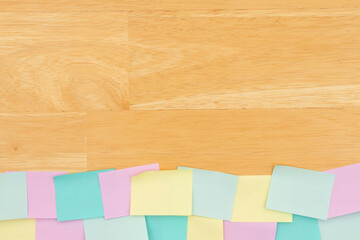 Sticky note background with multi-color notes on a wood desk