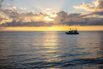 Sunrise sea landscape with wooden boat. Seaside travel photo. Ocean sunrise. Early morning seascape sun and cloud.