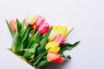 Beautiful tulips in bouquet lying on white background, top view