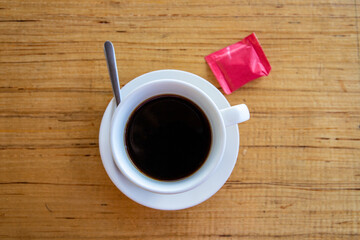 Black coffee in white cup on warm wooden table. Coffee drinking concept. Coffee cup and sugar top view photo