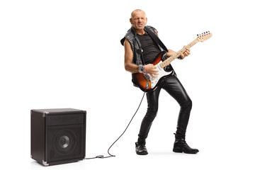 Bald musician playing a guitar plugged into an amplifier