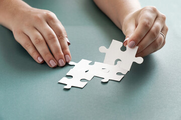 Concept of business, women hands holding  white puzzle pieces on the blue backgroud