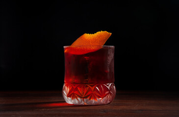 Boulevardier cocktail with orange peel garnish on a black background