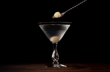 Gibson cocktail being finished with cocktail onions on a black background