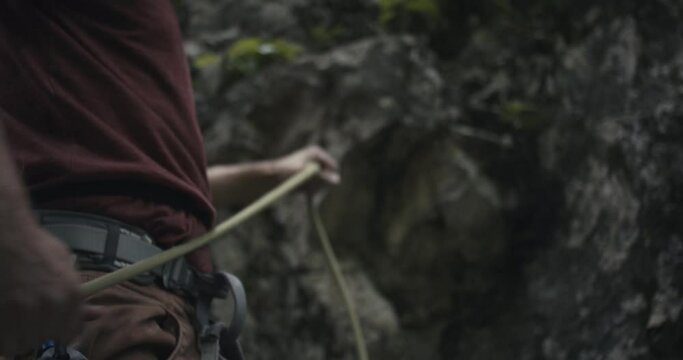 Climber detach pull belay lead rope after rock climbing by hand equipment safety gear outdoors lifestyle sport nature unrecognizable close up
