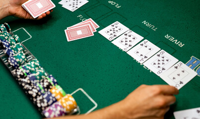 croupier on the poker table with a green cloth lays the card chips between his hands