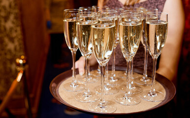 Full glasses of champagne on tray which hold waiter 