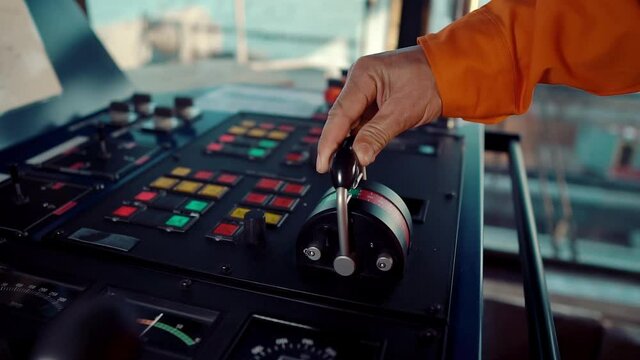Filipino deck Officer on bridge of vessel or ship wearing coverall during navigaton watch at sea . He is maneuvering with cpp thrusters propulsion