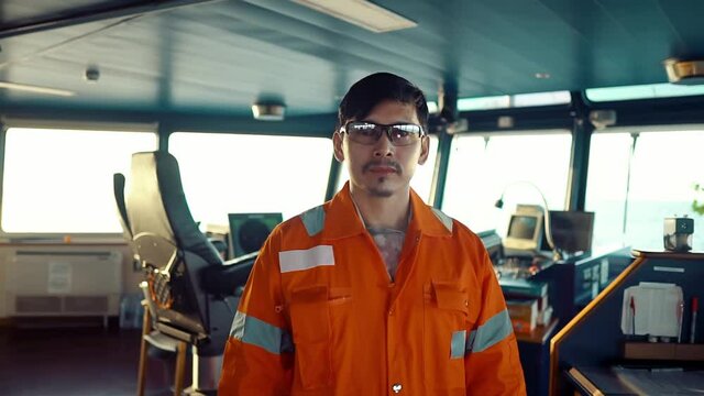 Filipino deck Officer on bridge of vessel or ship wearing coverall during navigaton watch at sea
