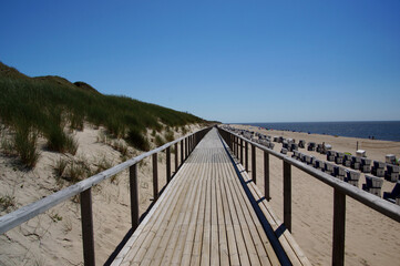 Fototapeta na wymiar Steg am Strand durch Sand, Uferpromenade, Sylt