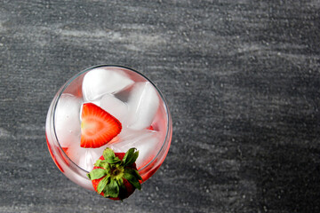 Gin tonic de fresa en mesa vintage y esferas rojas