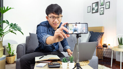 Asian blogger recording vlog video on camera review of product at home office
