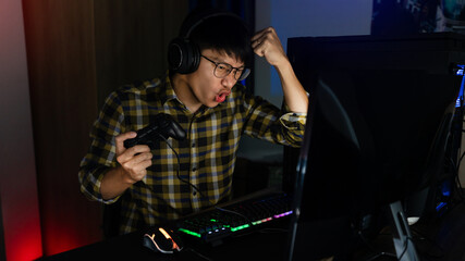 Fototapeta na wymiar Asian man cyber sport gamer concentrated playing video games on computer eSport concept